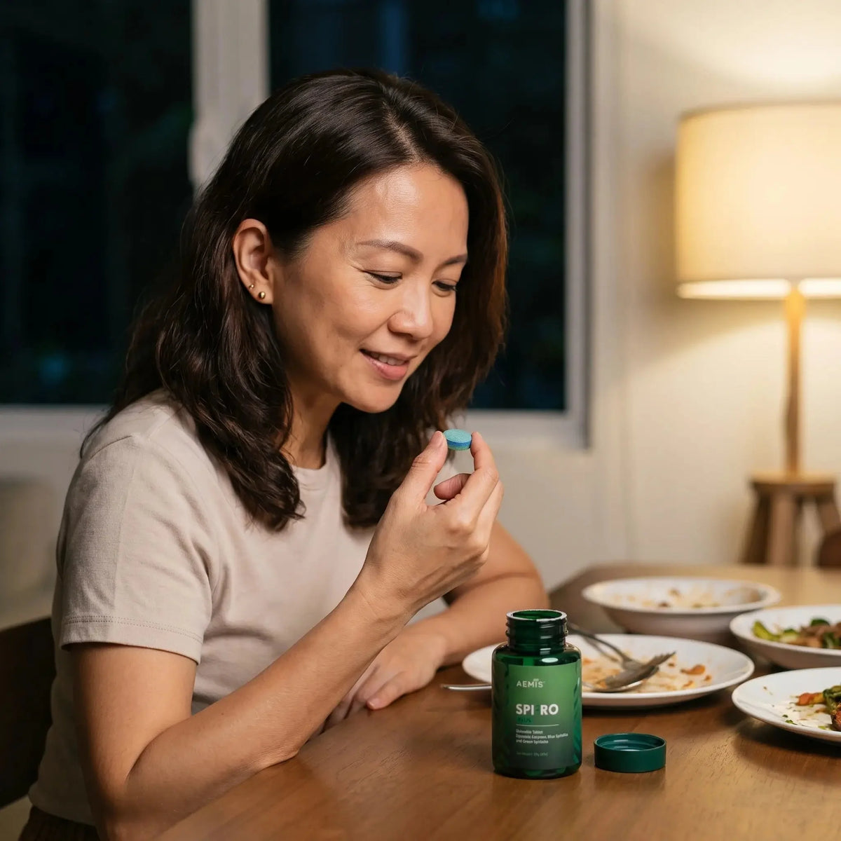 Woman taking a SpiroPlus tablet after dinner at home